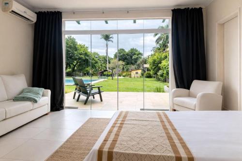 a bedroom with a bed and a couch and a patio at Sítio Mais Lindo do Mundo in Ilha de Guaratiba