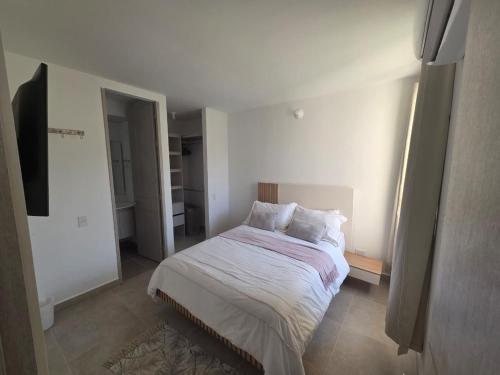 a bedroom with a large bed with white sheets and pillows at Sueños de Serena del Mar in Cartagena de Indias