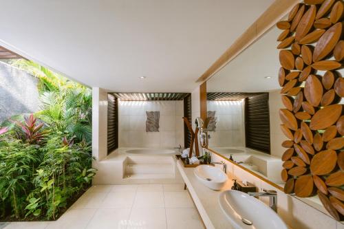 a bathroom with two sinks and a shower and a tub at MERUSAKA Nusa Dua in Nusa Dua