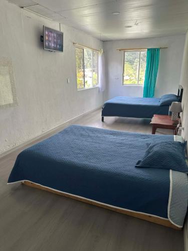 a bedroom with two beds and a tv on the wall at Villablanca in Cuenca
