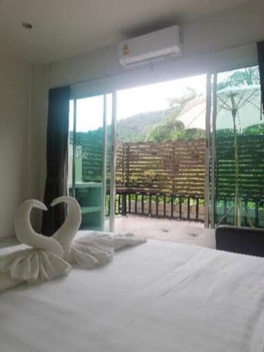 a bedroom with a bed with white sheets and a balcony at Katika Home 2 in Ban Khlong Haeng