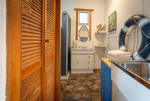 a bathroom with a sink and a wooden door at The Shack - Beachside At Binalong in Binalong Bay