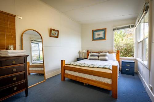 a bedroom with a bed and a dresser and a mirror at The Shack - Beachside At Binalong in Binalong Bay