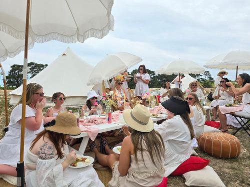 a group of people sitting at tables under umbrellas at Coastal Glamp at Bellarine Estate winery in Bellarine