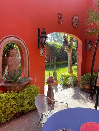 a red wall with a table and chairs in a yard at Hacienda Bugambilias Boutique Colonial in Cedro