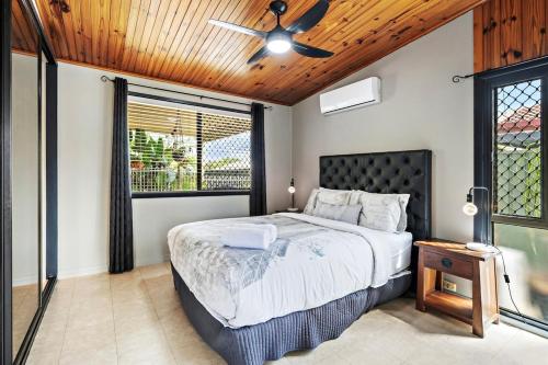 a bedroom with a bed and a ceiling fan at Pukeko Guesthouse - Relax in Redcliffe in Redcliffe