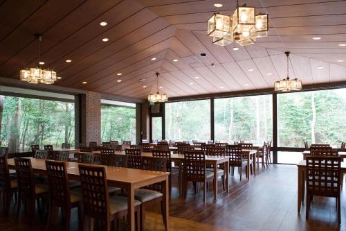 a dining room with tables and chairs and windows at Jiragonno Fuji no Yakata in Narusawa