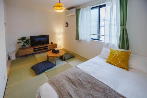 a bedroom with a bed with a television and a table at QH202 New Tokyo Apartment, Direct access to Ueno, Asakusa, Disneyland, Airport in Tokyo