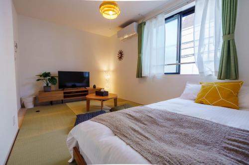 a bedroom with a large bed and a television at QH202 New Tokyo Apartment, Direct access to Ueno, Asakusa, Disneyland, Airport in Tokyo