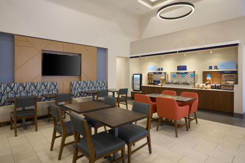 a dining room with tables and chairs and a tv at Holiday Inn Express Hotel & Suites Kendall East-Miami by IHG in Kendall
