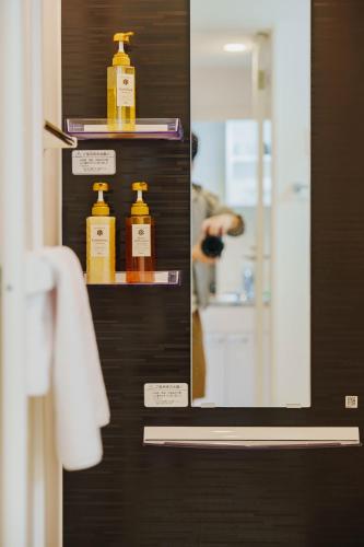 a mirror in a bathroom with three bottles of soap at QH302 New Tokyo Apartment, Direct access to Ueno, Asakusa, Disneyland, Airport in Tokyo