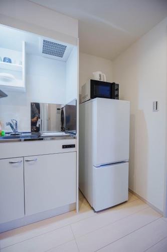 a kitchen with a white refrigerator and a sink at QH302 New Tokyo Apartment, Direct access to Ueno, Asakusa, Disneyland, Airport in Tokyo