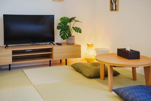 a living room with a television and a table at QH302 New Tokyo Apartment, Direct access to Ueno, Asakusa, Disneyland, Airport in Tokyo