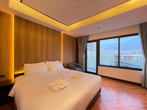 a bedroom with a large bed with a large window at Carista Hotel in Vientiane