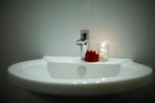 a bathroom sink with a candle and a red flower on it at Kandy Moon Hills Hotel in Kandy
