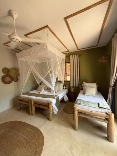 a bedroom with two beds and a mosquito net at Zen Boutique Retreat & Resort in Jambiani