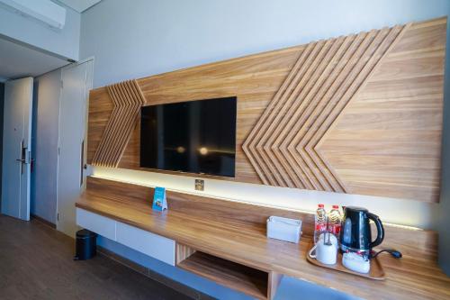 a room with a tv and a wooden wall at Facade Hotel by Azana in Tawangmangu