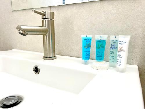 a sink with three bottles of hair products on it at MLQ Apartments by Avi in Grand-Baie
