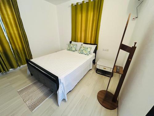 a small bedroom with a bed and yellow curtains at MLQ Apartments by Avi in Grand-Baie