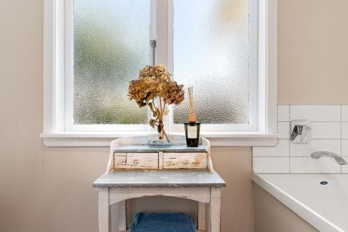 a table with a vase of flowers and a window at Sunset Villa in Martinborough