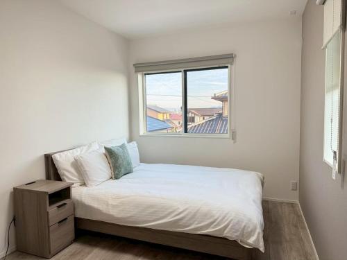a small bedroom with a bed with a window at Akikawa Koshi 13 新築木造一棟貸切ヴィラ in Yuge