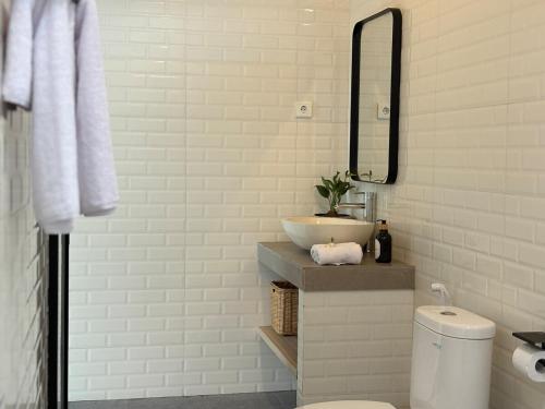 a white bathroom with a sink and a mirror at Umah Sepur Villa in Dalung