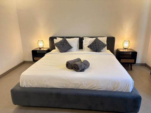 a bedroom with a large white bed with two lamps at Umah Sepur Villa in Dalung