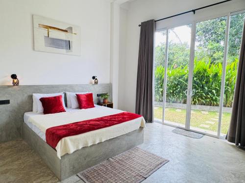 a bedroom with a bed with red pillows and a window at Bebe peak weligama in Weligama