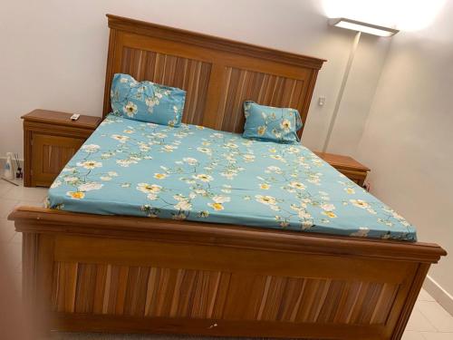 een bed met een houten frame en een blauw dekbed bij FassoImmoPrestige in Tambacounda