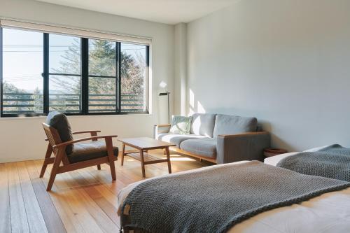 a living room with a couch and a chair at Tiny Garden Tateshina in Chino