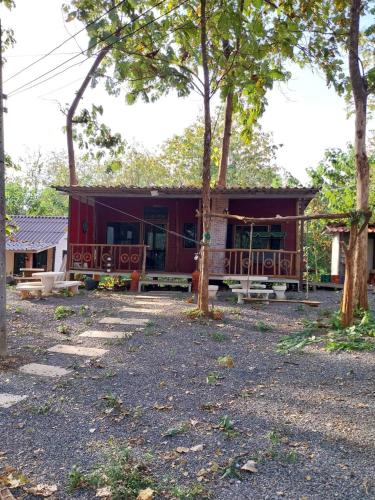 a red house with trees in front of it at ดงสัก สไตล์ป่า ไทรโยคน้อย in Ban Phu Pla Kang