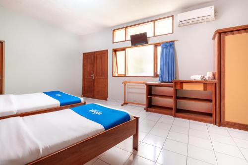 a bedroom with two beds and a desk and a window at Rehat at Abadi Hotel Tasikmalaya in Tasikmalaya