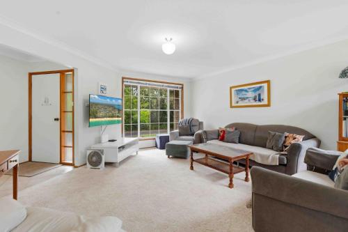 a living room with two couches and a table at Peace by the Beach by Experience Jervis Bay in Vincentia
