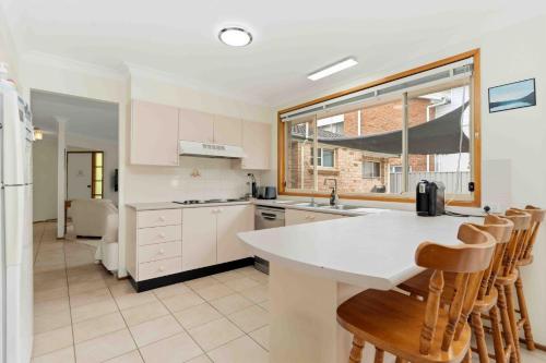 a kitchen with a counter and some chairs in it at Peace by the Beach by Experience Jervis Bay in Vincentia