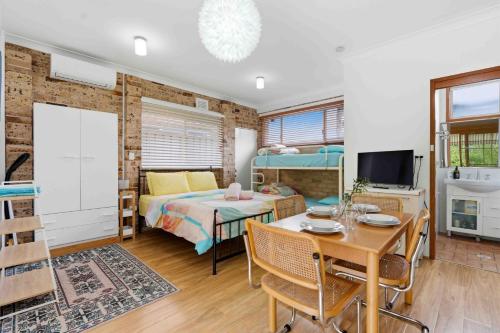 a bedroom with a bed and a table and a dining room at Peace by the Beach by Experience Jervis Bay in Vincentia