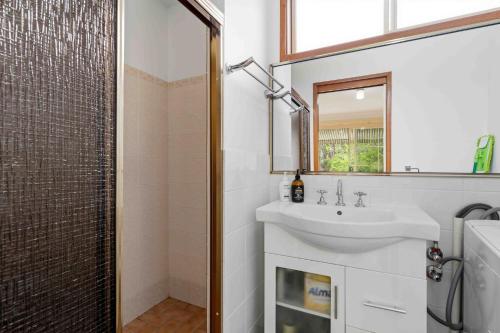 a bathroom with a sink and a shower with a mirror at Peace by the Beach by Experience Jervis Bay in Vincentia