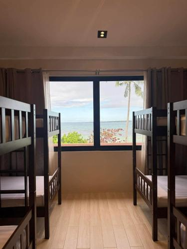 a room with two bunk beds and a window with the ocean at Chellie Rose Resort Hotel in Bantayan Island