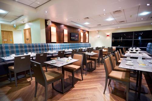 a dining room with tables and chairs in a restaurant at The Warwickshire Hotel and Country Club in Warwick
