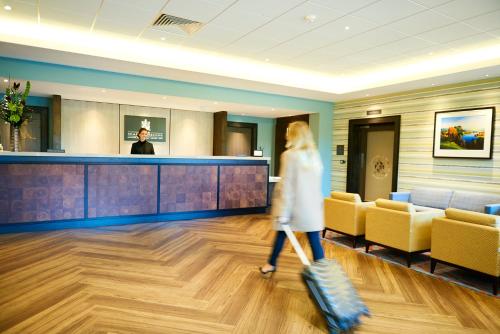 a woman walking through the lobby of a hospital at The Warwickshire Hotel and Country Club in Warwick