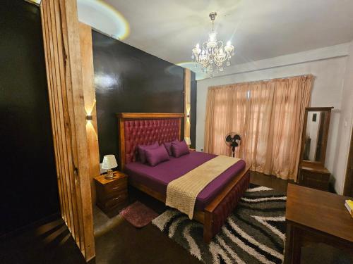 a bedroom with a purple bed and a chandelier at Bloomy villa in Hatton
