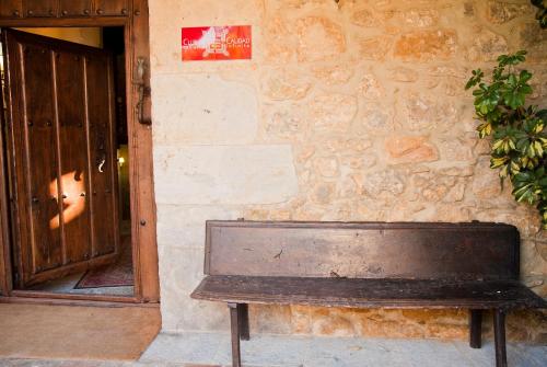 a wooden bench sitting in front of a building with a door at La Casa del Organista in Santillana del Mar