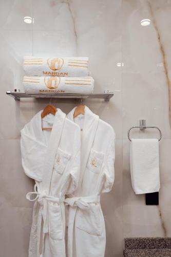 a closet with white robes and towels on a shelf at Mardan Hotel in Shymkent