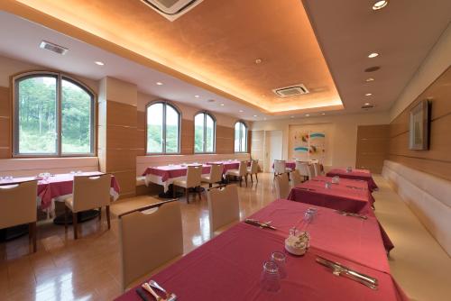 a restaurant with red tables and chairs and windows at Scenery Resort Suruga in Numazu