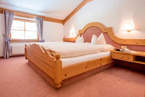 a bedroom with a large bed with a wooden headboard at Landhotel Älpili in Gaschurn