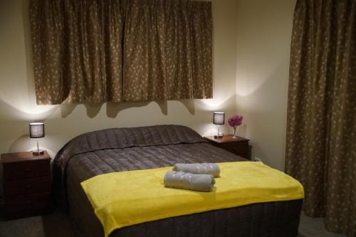 a bedroom with a bed with a yellow blanket and two lamps at A Touch of Class in Greymouth