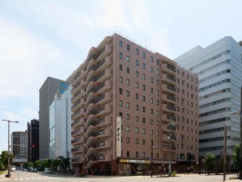 a tall building on a city street with tall buildings at Via Inn Shin-Osaka West in Osaka