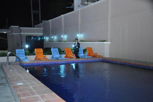 a man standing next to chairs and a swimming pool at Citiheight Hotel in Ikeja