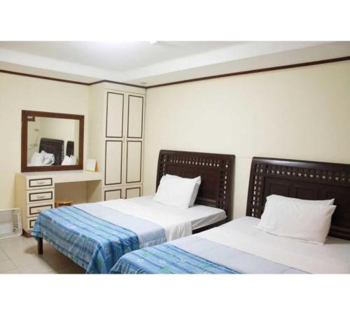 a bedroom with two beds and a mirror at OYO 1202 Shilla Hotel in Pampang