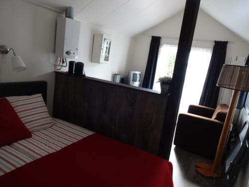 een slaapkamer met een bed, een stoel en een raam bij Peter&Trienke's Bed&Brochje in Stiens