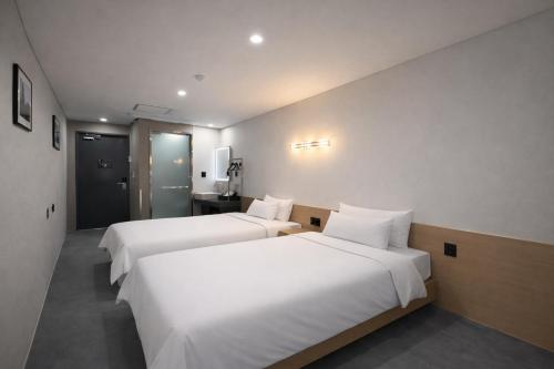 two beds in a hotel room with white sheets at JE JA RI Stay in Seoul